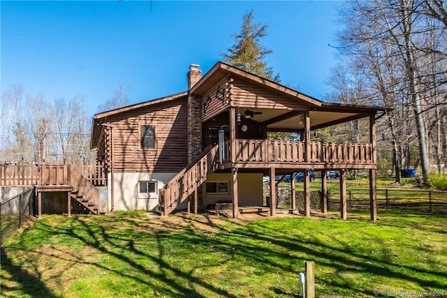 back of house featuring a lawn, ceiling fan, and a wooden deck