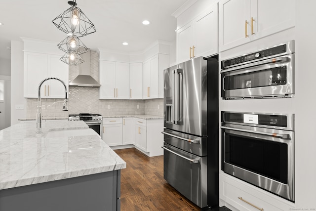 kitchen with wall chimney exhaust hood, white cabinets, high quality appliances, pendant lighting, and dark hardwood / wood-style flooring