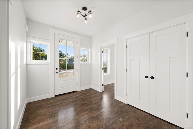 foyer entrance with dark hardwood / wood-style floors and a chandelier