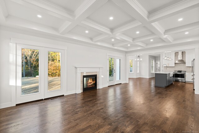 unfurnished living room with sink, ornamental molding, beam ceiling, coffered ceiling, and dark wood-type flooring