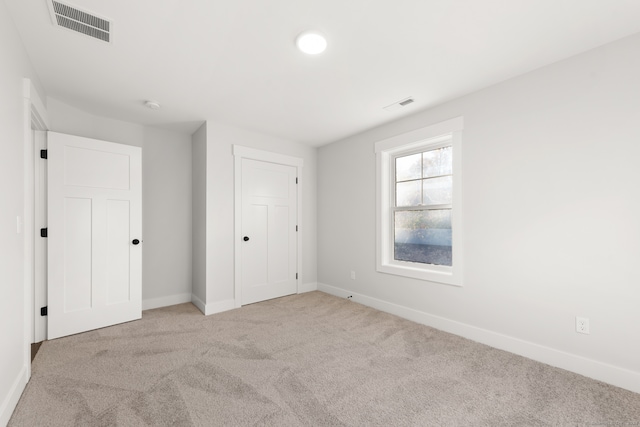 unfurnished bedroom featuring light carpet and a closet