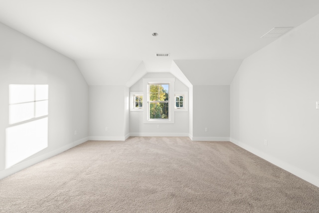 bonus room with lofted ceiling and light carpet