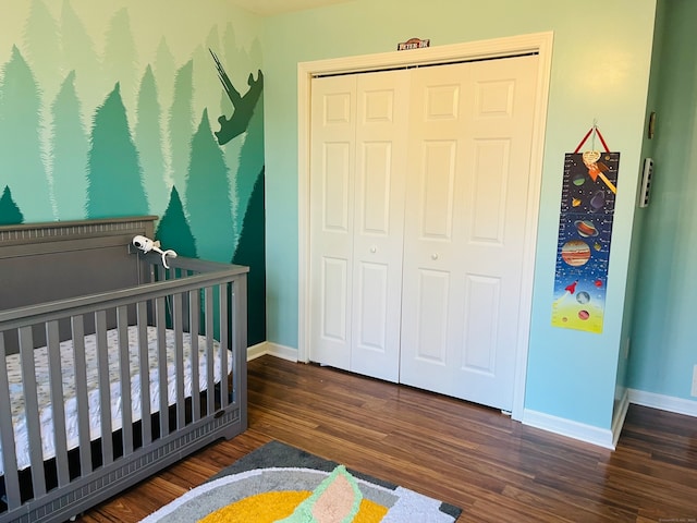 bedroom featuring a crib, dark hardwood / wood-style flooring, and a closet