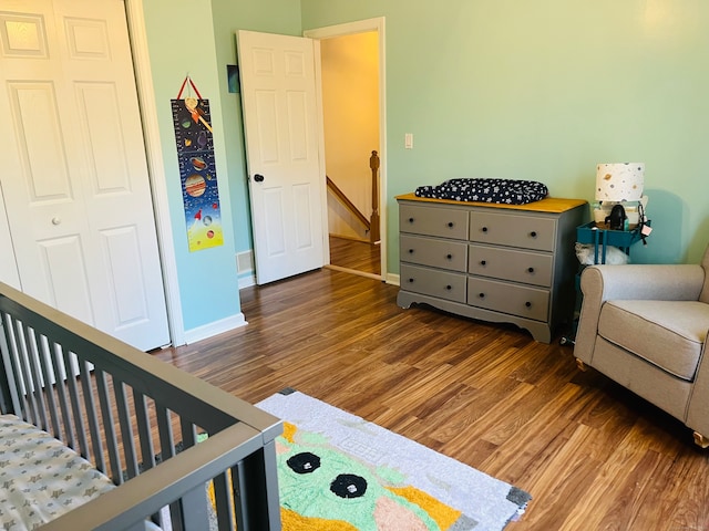 bedroom with a closet, a nursery area, and dark wood-type flooring