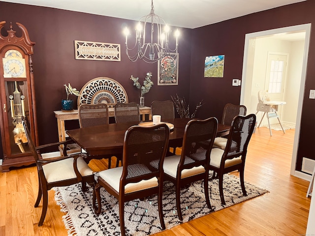 dining space with wood-type flooring and an inviting chandelier