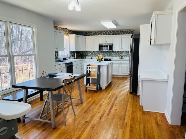 kitchen featuring appliances with stainless steel finishes, backsplash, sink, light hardwood / wood-style flooring, and white cabinets