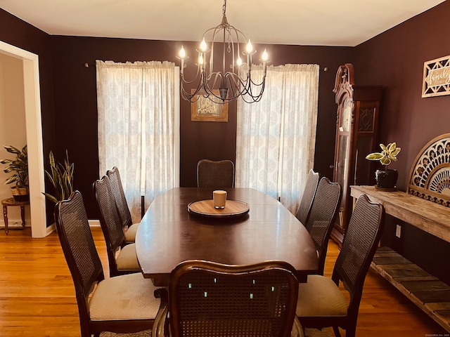 dining space with light hardwood / wood-style floors, a healthy amount of sunlight, and a chandelier