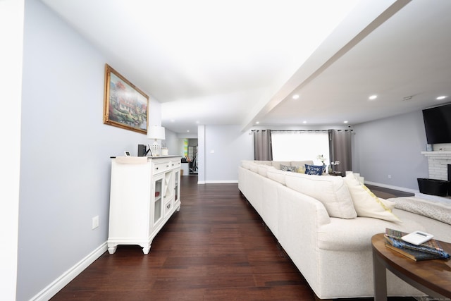 living room featuring a brick fireplace and dark wood-type flooring