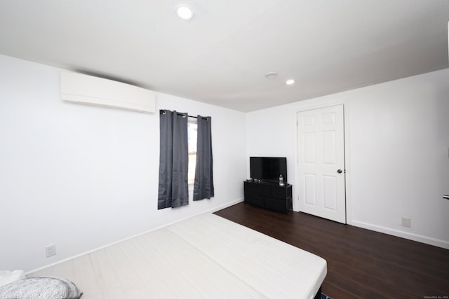 unfurnished bedroom with a wall mounted air conditioner and dark wood-type flooring