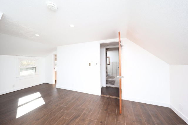 additional living space featuring a textured ceiling, vaulted ceiling, and dark wood-type flooring