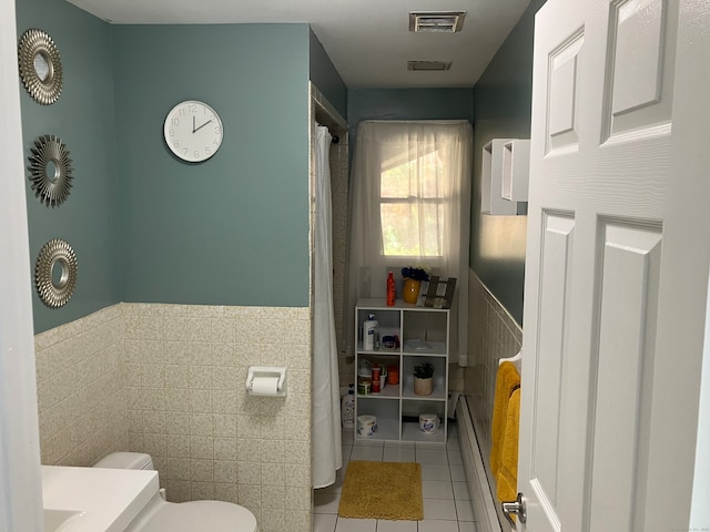 bathroom featuring tile patterned flooring, toilet, tile walls, and a baseboard radiator