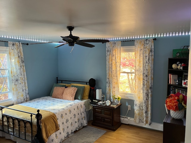 bedroom with ceiling fan, light hardwood / wood-style floors, and baseboard heating