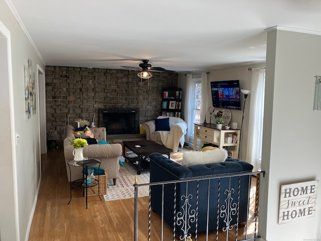 living room featuring a brick fireplace, ceiling fan, ornamental molding, and hardwood / wood-style flooring