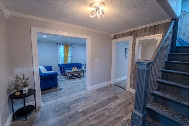 interior space with a textured ceiling, hardwood / wood-style flooring, and crown molding