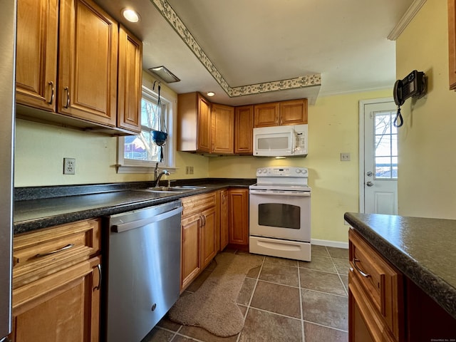 kitchen featuring a wealth of natural light, sink, white appliances, dark tile patterned flooring, and ornamental molding