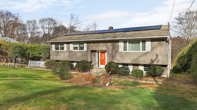 split foyer home featuring a front yard and solar panels