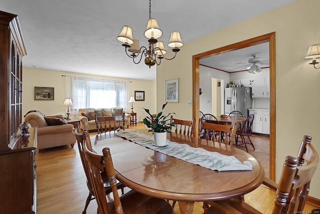 dining room with ceiling fan with notable chandelier and light hardwood / wood-style flooring