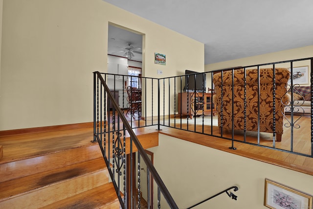 staircase featuring wood-type flooring and ceiling fan