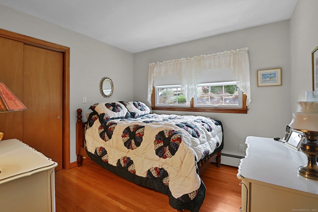 bedroom with a baseboard radiator and light hardwood / wood-style flooring