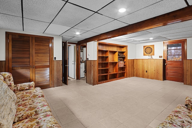 living room featuring a drop ceiling and wooden walls