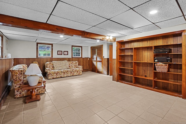 sitting room with a drop ceiling and wooden walls