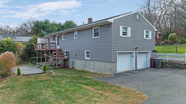 rear view of house with a garage, a wooden deck, and a lawn