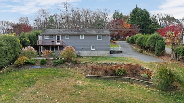 rear view of house with a wooden deck and a yard