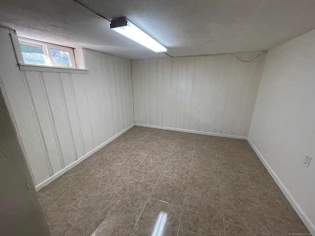 basement featuring a textured ceiling and wood walls