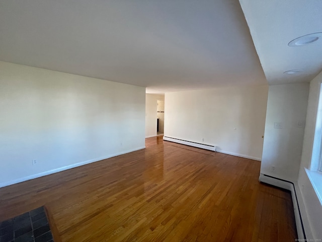 unfurnished room featuring dark hardwood / wood-style flooring and a baseboard heating unit