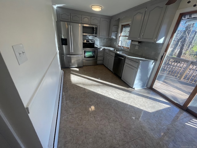 kitchen featuring appliances with stainless steel finishes, backsplash, a baseboard heating unit, sink, and gray cabinets