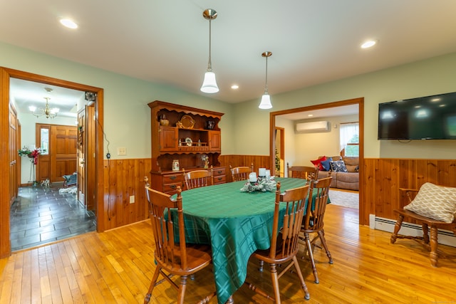 dining space featuring light hardwood / wood-style flooring, a notable chandelier, and a wall unit AC