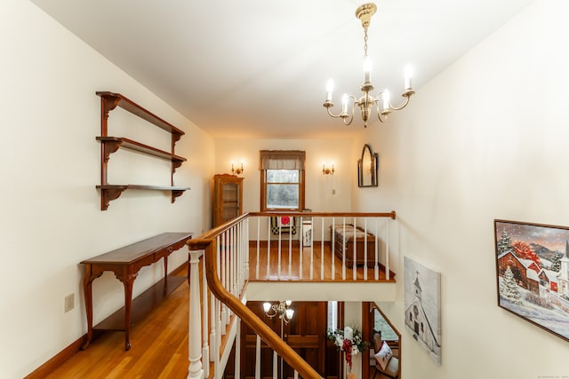 staircase featuring hardwood / wood-style flooring and an inviting chandelier