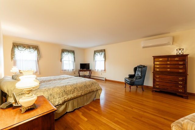 bedroom featuring hardwood / wood-style flooring, a wall unit AC, and a baseboard heating unit