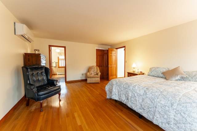 bedroom featuring connected bathroom, a wall mounted AC, wood-type flooring, and a baseboard radiator