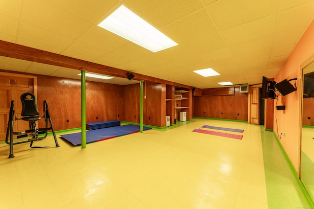 exercise area with wooden walls and a drop ceiling