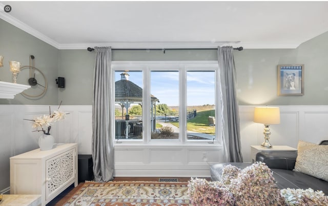 interior space with visible vents, ornamental molding, wainscoting, a decorative wall, and wood finished floors