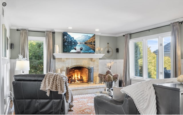 interior space featuring crown molding, a wainscoted wall, a lit fireplace, and recessed lighting