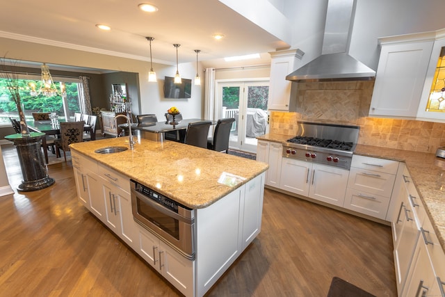 kitchen with a sink, stainless steel gas stovetop, dark wood-style floors, and wall chimney exhaust hood
