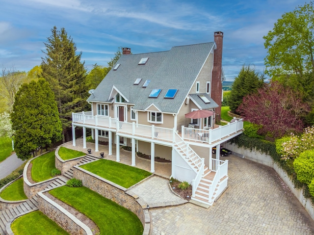 rear view of house with a chimney, a wooden deck, and stairway