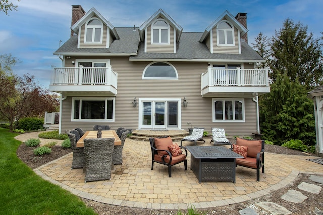 rear view of property with a patio, a chimney, an outdoor living space, and a balcony
