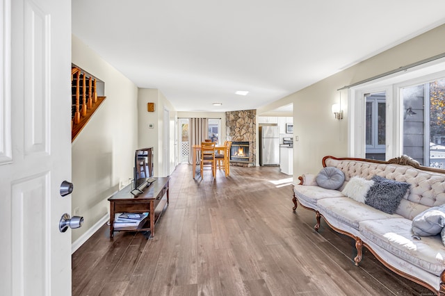 living room featuring a stone fireplace and wood-type flooring