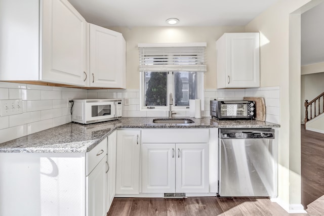 kitchen with light stone countertops, dark hardwood / wood-style flooring, sink, dishwasher, and white cabinetry