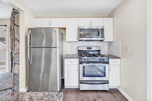 kitchen featuring white cabinets, dark hardwood / wood-style flooring, stainless steel appliances, and dark stone counters