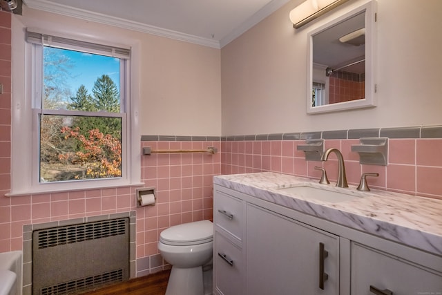 bathroom featuring radiator, vanity, crown molding, toilet, and tile walls