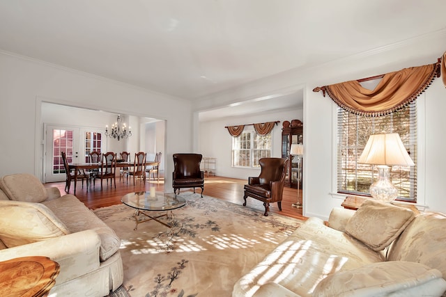 living room featuring ornamental molding, hardwood / wood-style flooring, french doors, and a notable chandelier