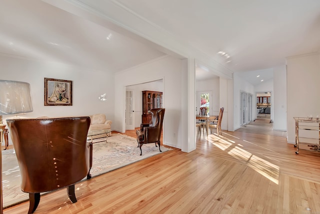 sitting room featuring light wood-type flooring, vaulted ceiling, and ornamental molding