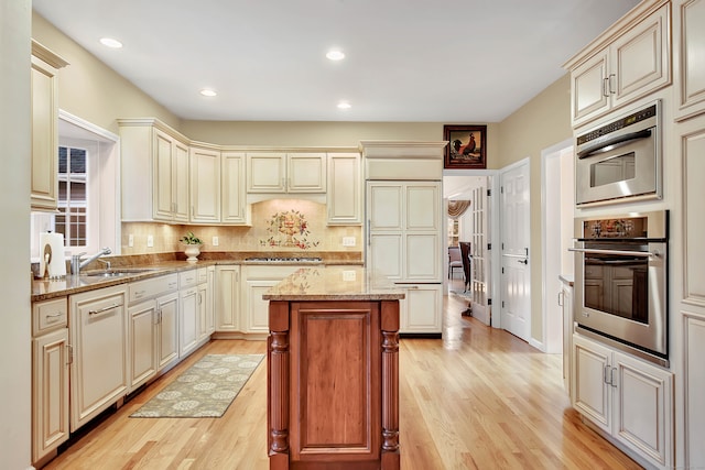 kitchen featuring light stone counters, light hardwood / wood-style flooring, backsplash, cream cabinetry, and a kitchen island