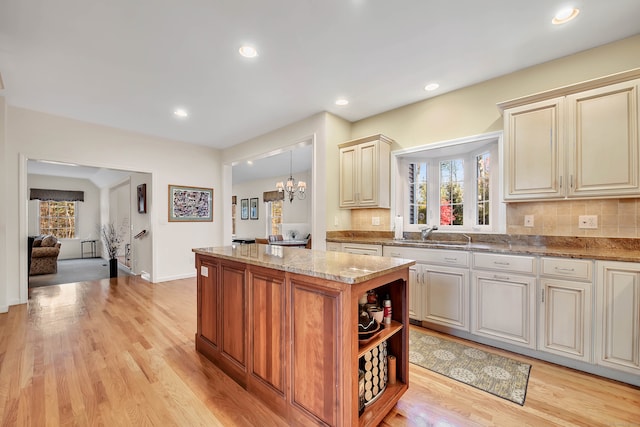 kitchen with cream cabinets, light wood-type flooring, a kitchen island, and sink