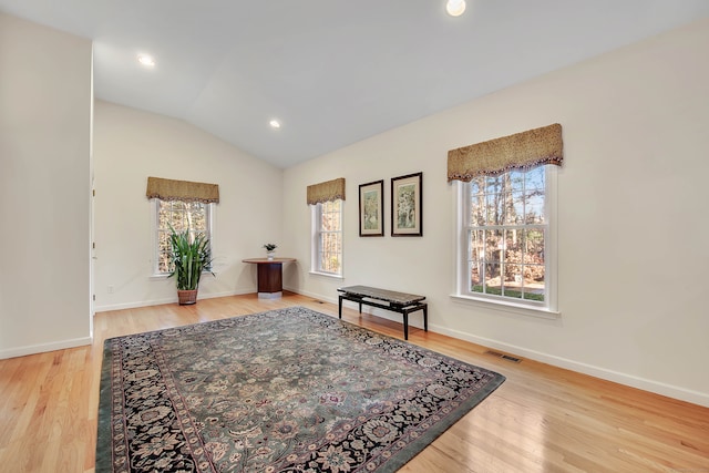 living area with a healthy amount of sunlight, lofted ceiling, and light hardwood / wood-style floors