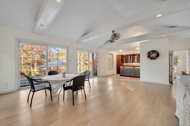 dining space featuring vaulted ceiling with beams and light hardwood / wood-style flooring